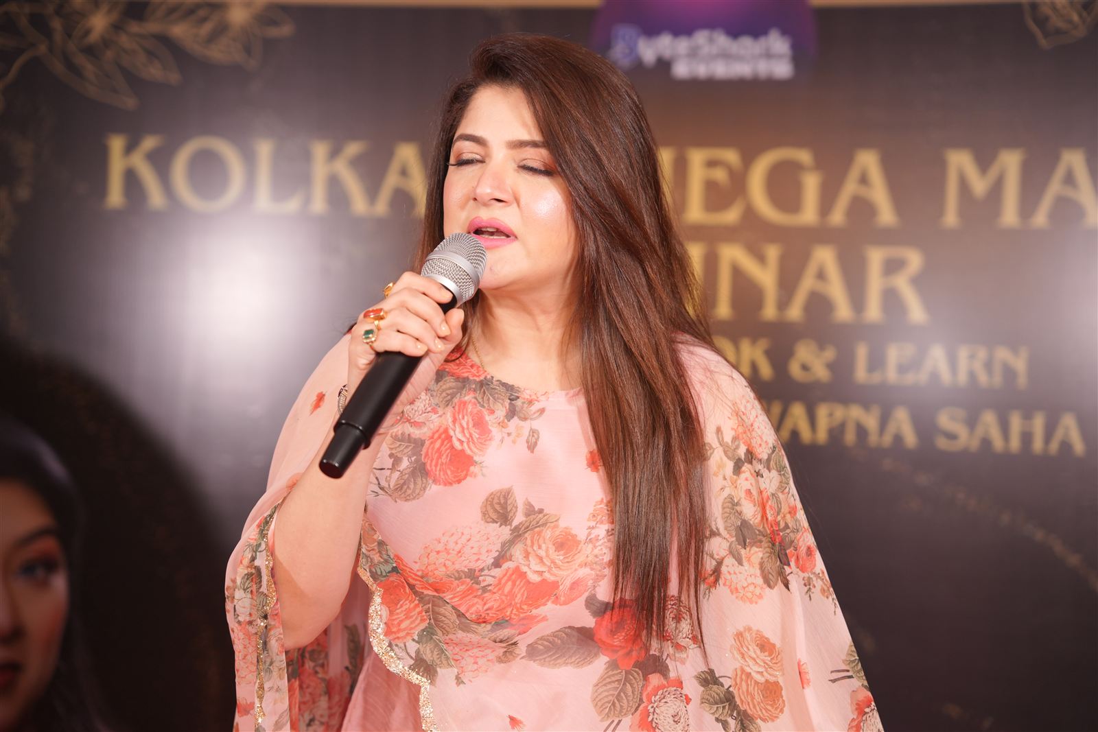 Guest speaking on stage in front of the Kolkata Mega Makeup Seminar backdrop